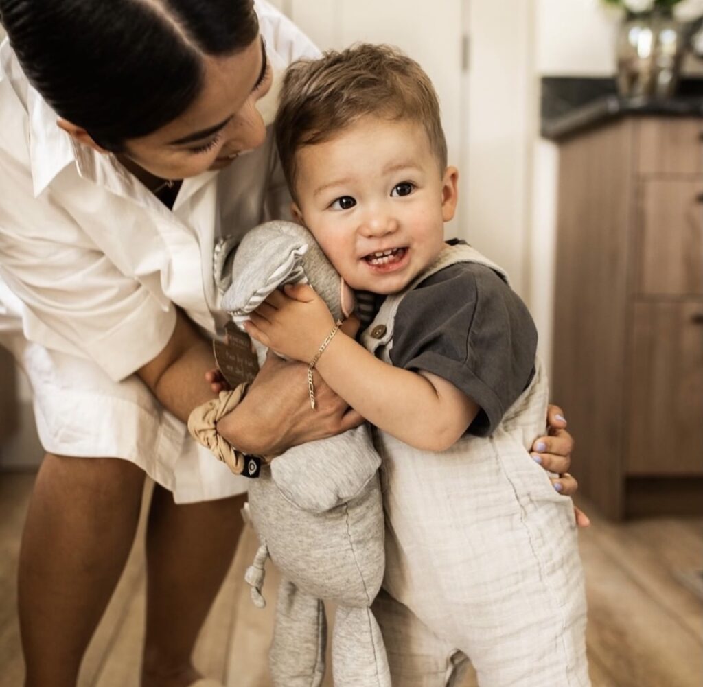 mother and child smiling and holding stuffed toy